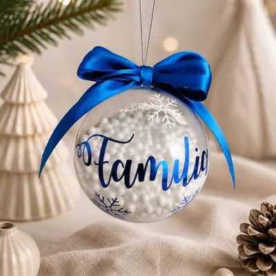 Bola de Navidad transparente rellena de perlas blancas, con la palabra Familia en azul y copos de nieve