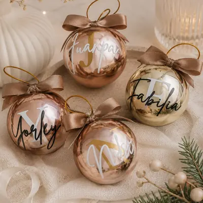 Cuatro bolas de Navidad doradas y cobre con nombres personalizados en vinilo y lazos de satín