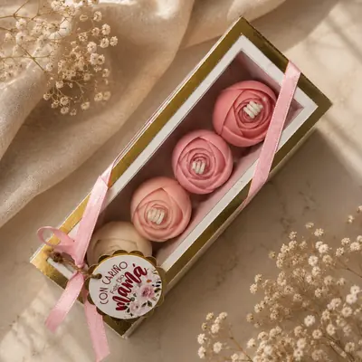 Caja alargada con borde dorado y cuatro velas con forma de rosa rosada, con tarjeta Feliz Día Mamá