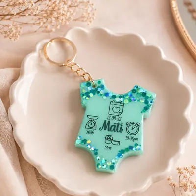 Llavero de resina con forma de body de bebé en verde menta con glitter, con el nombre y los datos de nacimiento
