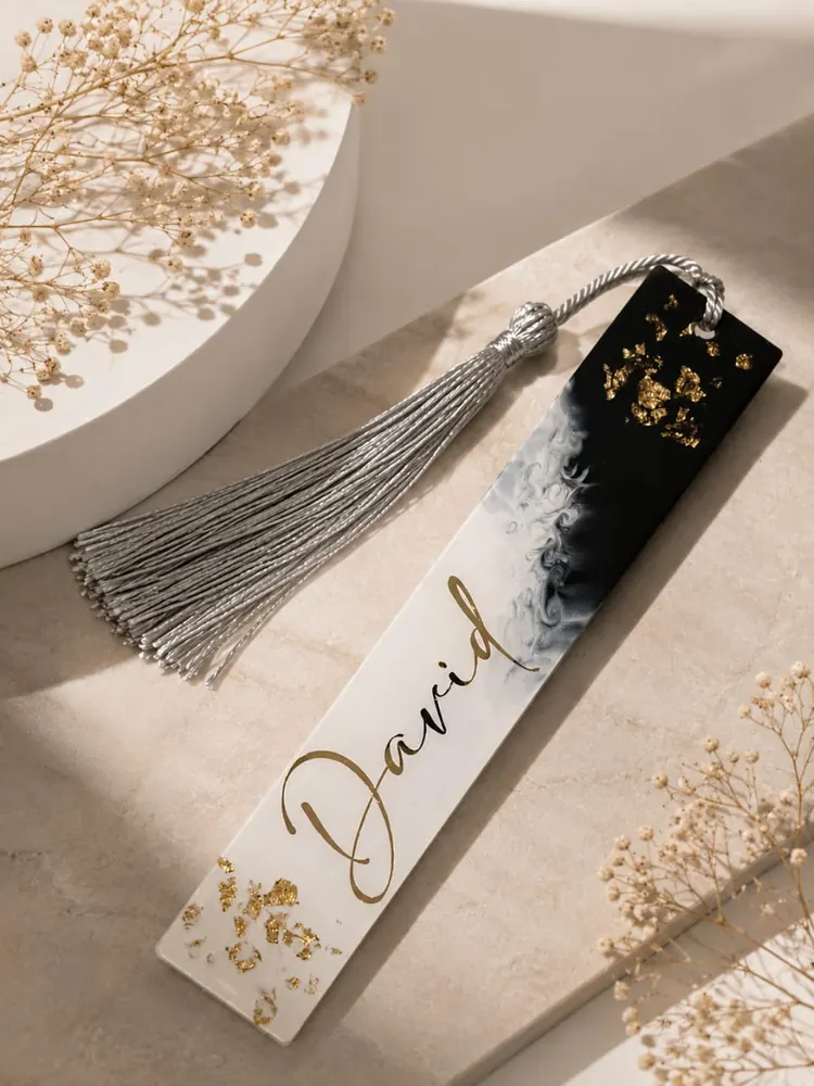 Marca páginas de resina con mármol blanco y negro, hoja de oro y el nombre en dorado, con borla plateada