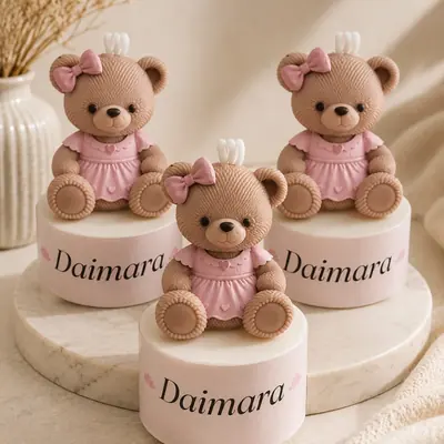 Velas con forma de osita con vestido rosa y moño, sobre base con el nombre Daimara