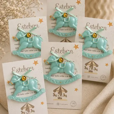 Vela con forma de caballito mecedor verde menta con cascabel dorado, montadas sobre tarjetas con el nombre Esteban