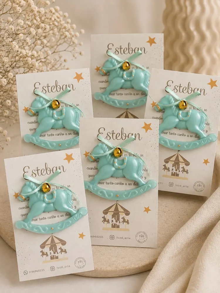 Vela con forma de caballito mecedor verde menta con cascabel dorado, montadas sobre tarjetas con el nombre Esteban