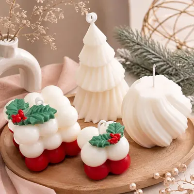 Velas de Navidad en cera blanca: un árbol escalonado, una esfera tipo concha y dos cubos de burbujas con acebo